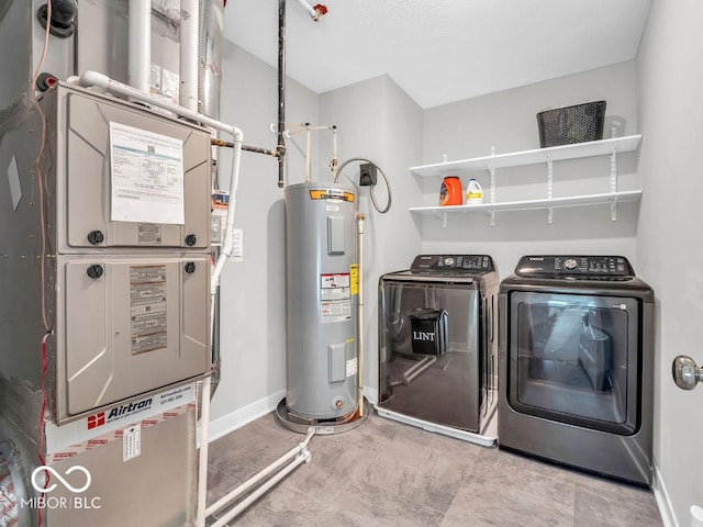 laundry area featuring washing machine and clothes dryer, electric water heater, and heating unit