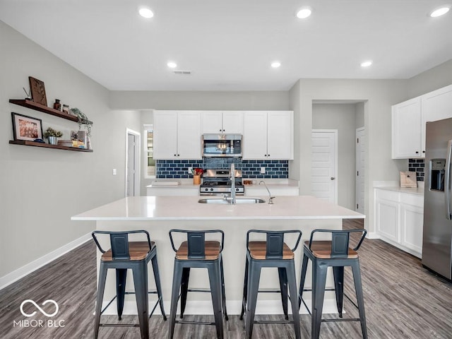 kitchen featuring sink, a center island with sink, appliances with stainless steel finishes, dark hardwood / wood-style floors, and white cabinets