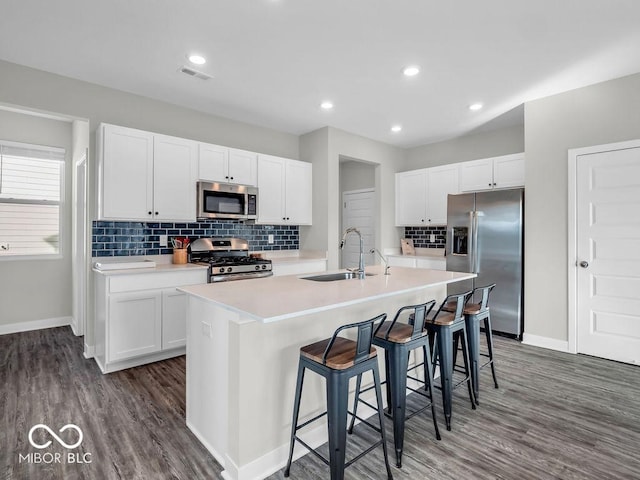 kitchen featuring sink, appliances with stainless steel finishes, white cabinetry, an island with sink, and a kitchen bar