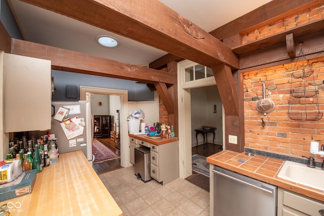 kitchen featuring sink, butcher block countertops, appliances with stainless steel finishes, beamed ceiling, and white cabinets