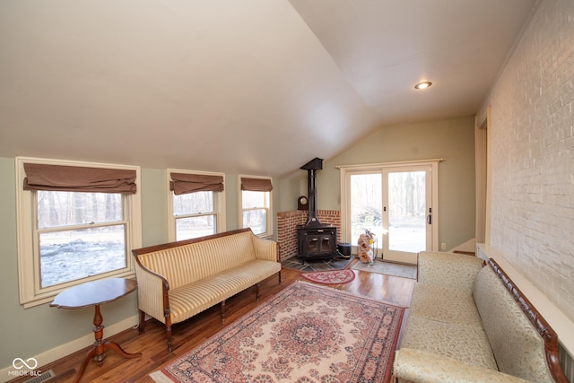 living room featuring hardwood / wood-style flooring, lofted ceiling, and a wood stove