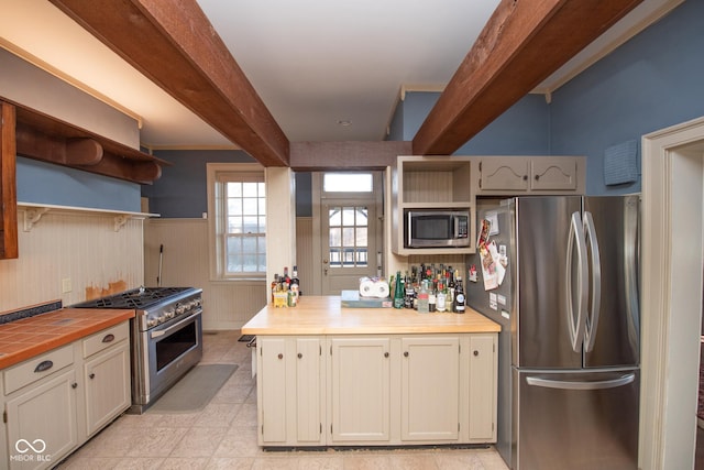 kitchen featuring wood walls, wooden counters, beamed ceiling, and appliances with stainless steel finishes