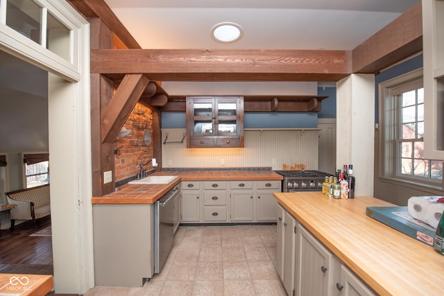 kitchen featuring wooden counters, beam ceiling, dishwasher, and sink