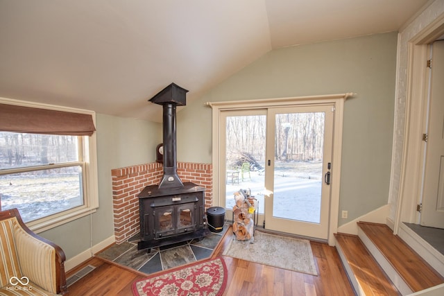 living room with hardwood / wood-style flooring, vaulted ceiling, and a wood stove