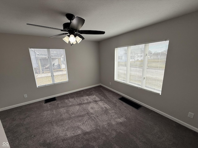 spare room featuring ceiling fan, a textured ceiling, and dark colored carpet