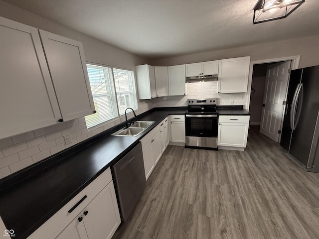 kitchen with sink, light hardwood / wood-style flooring, appliances with stainless steel finishes, tasteful backsplash, and white cabinets