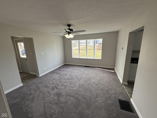 unfurnished living room with ceiling fan, a textured ceiling, and dark colored carpet