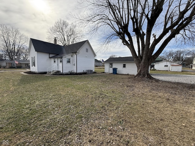 view of side of home featuring central AC unit and a yard