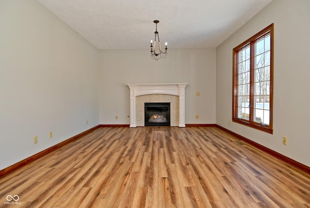 unfurnished living room with a fireplace, light hardwood / wood-style flooring, and a chandelier