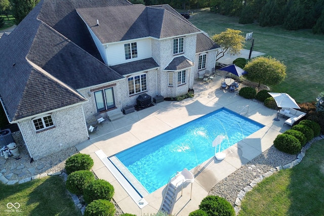 view of pool featuring a grill, a lawn, and a patio