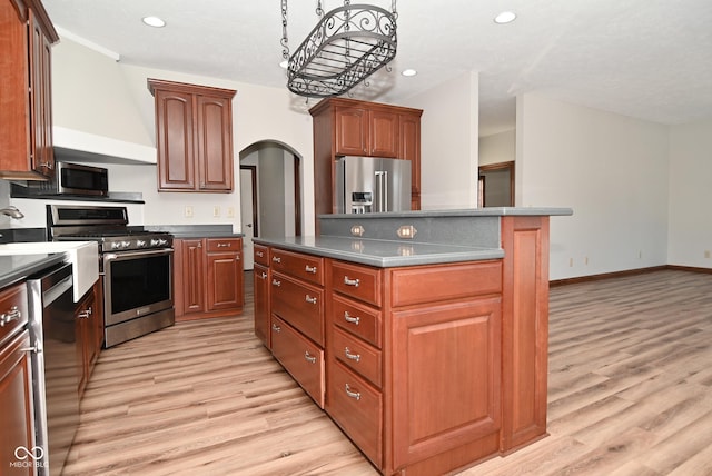 kitchen featuring stainless steel appliances, a kitchen island, and light wood-type flooring