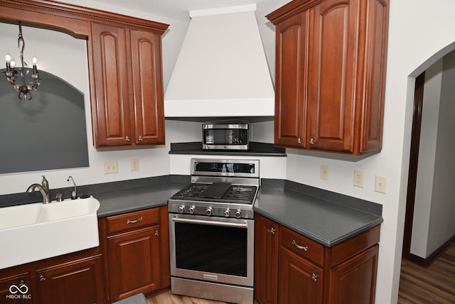 kitchen featuring sink, a chandelier, appliances with stainless steel finishes, custom range hood, and hardwood / wood-style floors