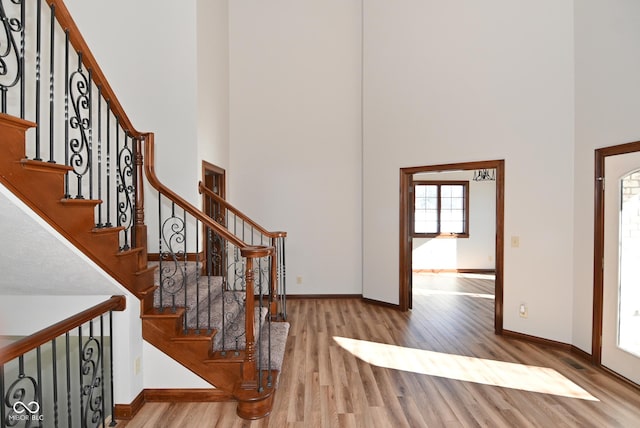 staircase with hardwood / wood-style flooring and a high ceiling