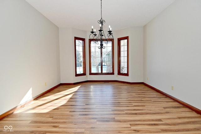 empty room featuring a chandelier and light wood-type flooring