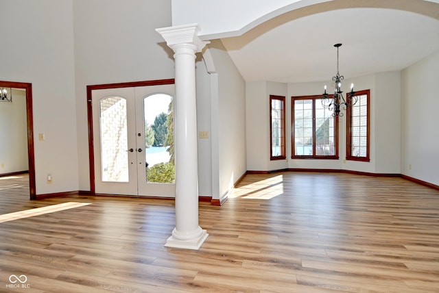 foyer featuring decorative columns, a notable chandelier, light hardwood / wood-style floors, and french doors