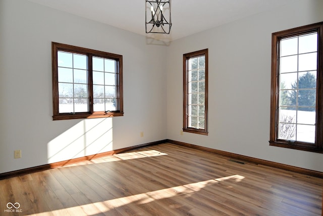 unfurnished room with hardwood / wood-style floors and an inviting chandelier