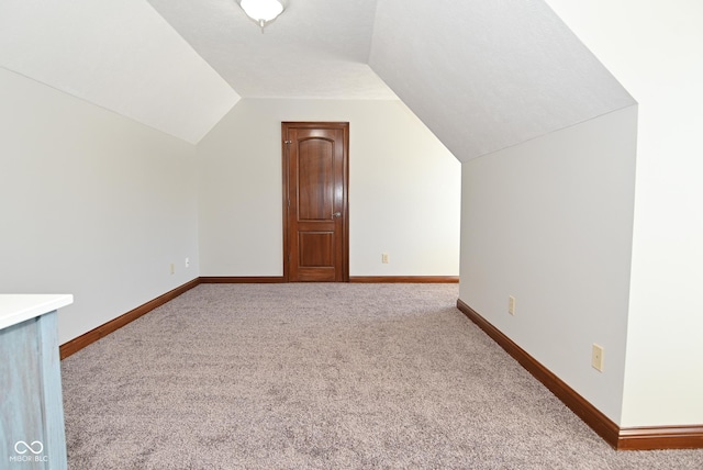 bonus room with lofted ceiling and light colored carpet