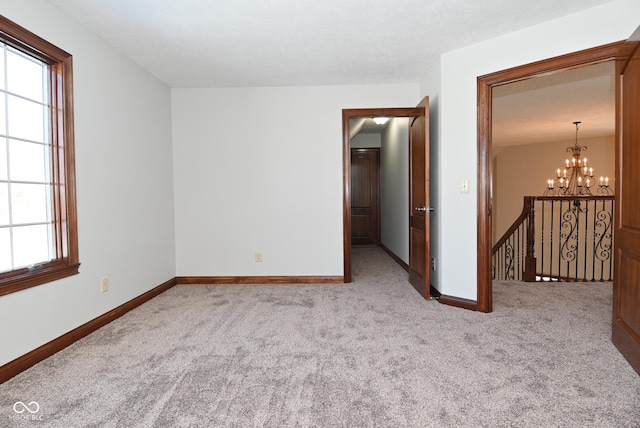 spare room featuring a chandelier and light carpet