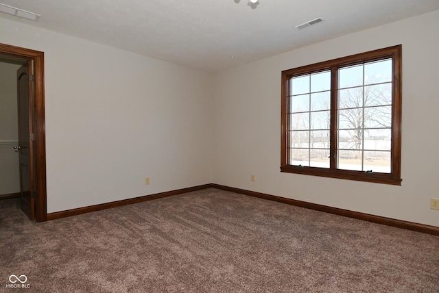 unfurnished room featuring plenty of natural light and dark carpet