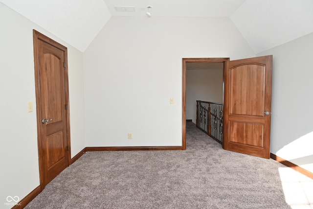 carpeted spare room featuring vaulted ceiling