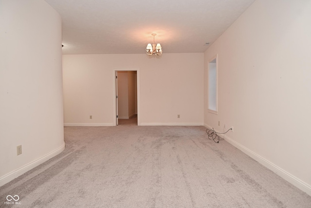 empty room featuring an inviting chandelier and light colored carpet