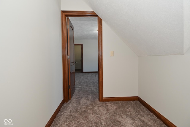 additional living space with lofted ceiling, dark carpet, and a textured ceiling