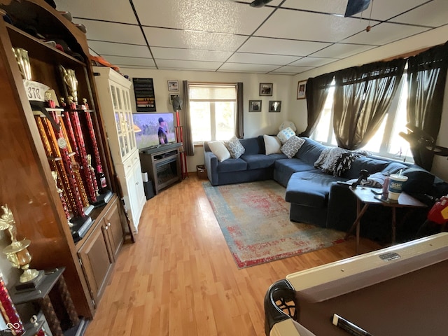 living room with a drop ceiling and light wood-type flooring