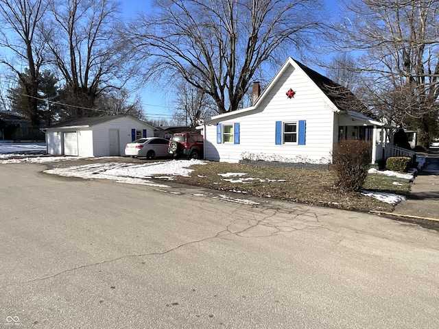 view of snowy exterior featuring an outbuilding and a garage