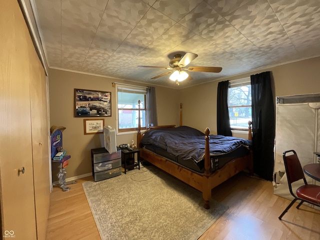 bedroom featuring multiple windows, crown molding, hardwood / wood-style floors, and ceiling fan