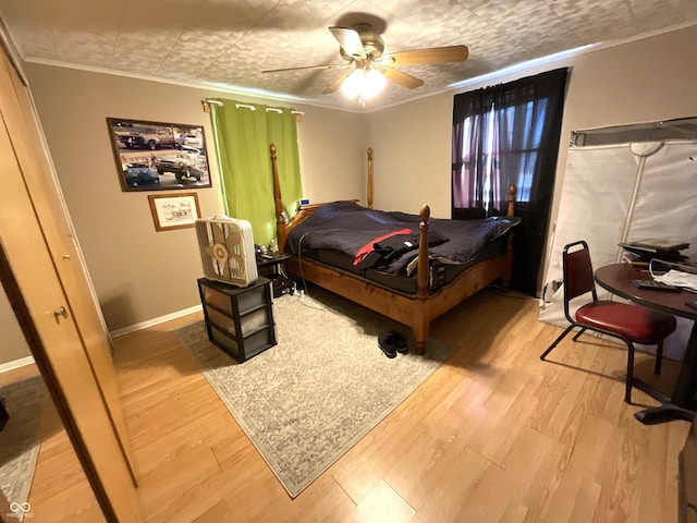 bedroom with ceiling fan, ornamental molding, and wood-type flooring