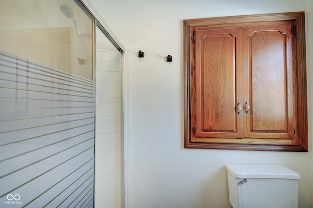 bathroom with a shower with door and toilet