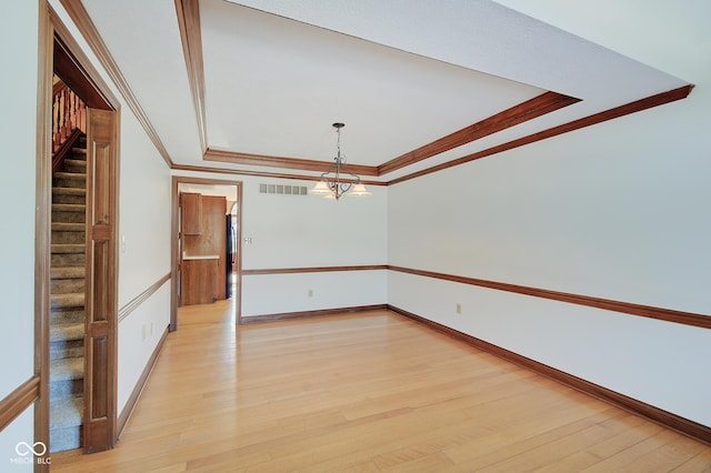 unfurnished room featuring a raised ceiling, crown molding, and light hardwood / wood-style flooring