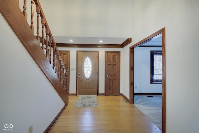 foyer entrance with ornamental molding and light wood-type flooring