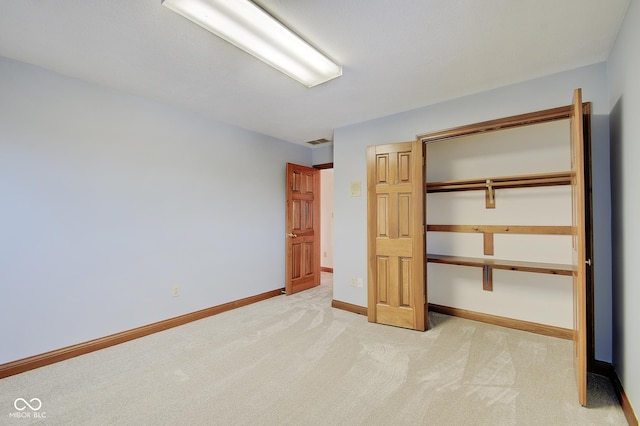 unfurnished bedroom with light carpet and a closet