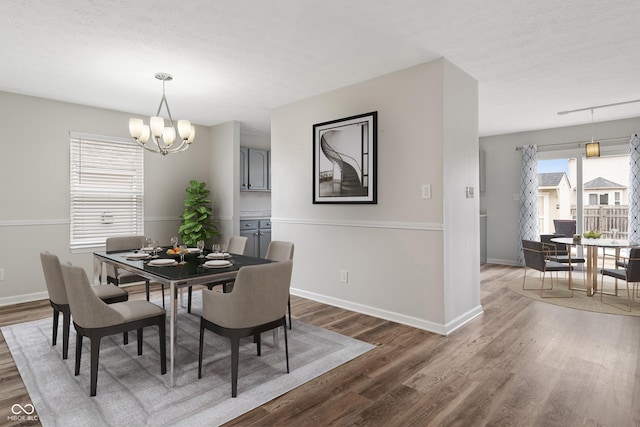 dining space featuring a notable chandelier, dark wood-type flooring, and a textured ceiling