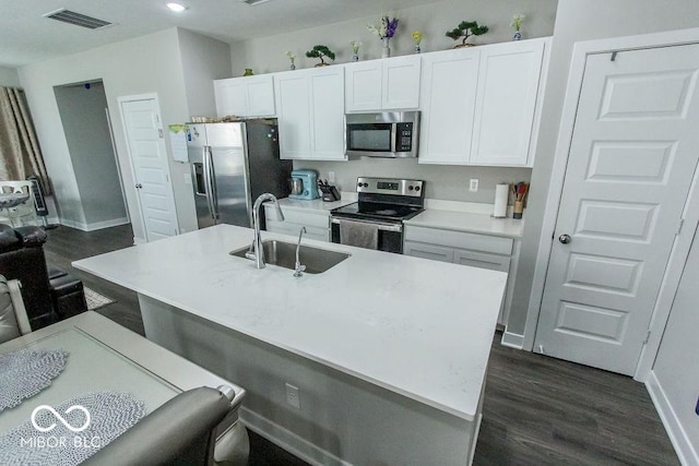 kitchen featuring a kitchen bar, sink, a center island with sink, appliances with stainless steel finishes, and white cabinets