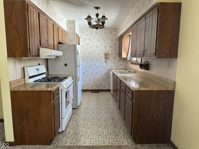 kitchen featuring white gas range, sink, and a chandelier