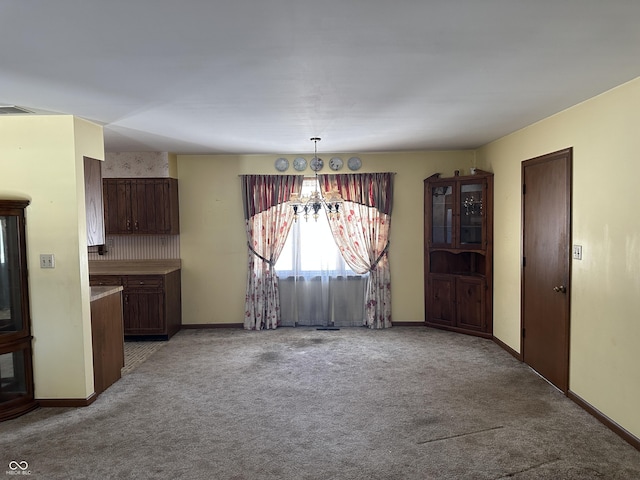 unfurnished dining area featuring light colored carpet and a chandelier