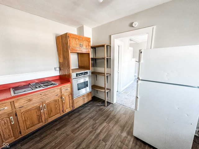 kitchen with cooktop, dark hardwood / wood-style floors, oven, and white refrigerator