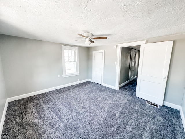 unfurnished bedroom with a textured ceiling, ceiling fan, and dark colored carpet