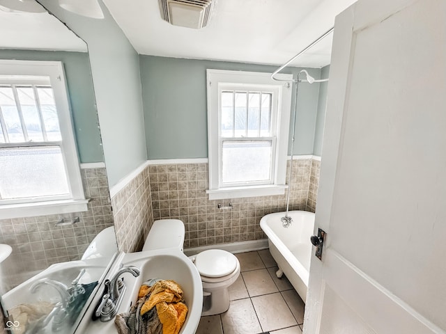 bathroom featuring plenty of natural light, tile walls, a washtub, and tile patterned floors