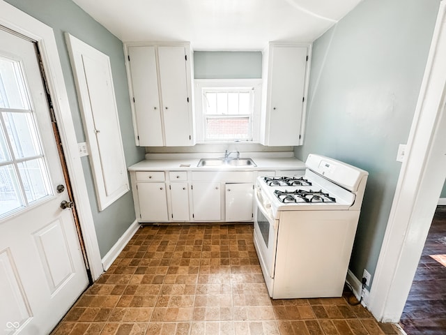 kitchen with sink, white gas stove, and white cabinets