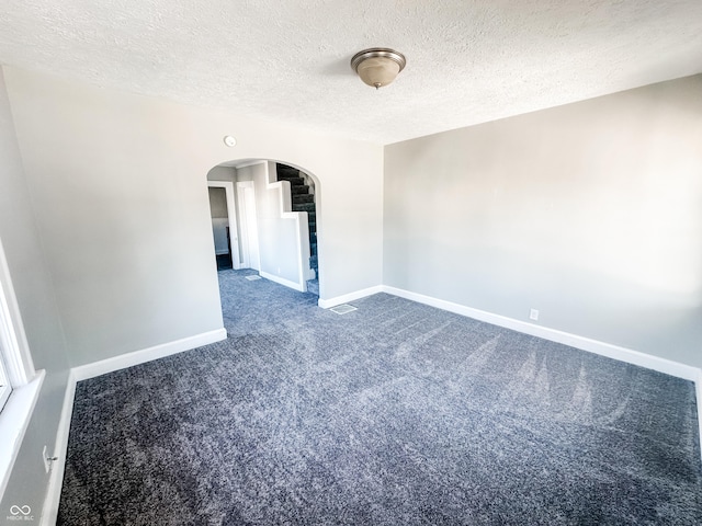 empty room featuring dark carpet and a textured ceiling