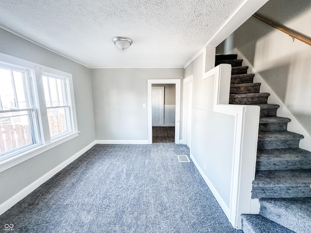 interior space with ornamental molding, carpet, and a textured ceiling