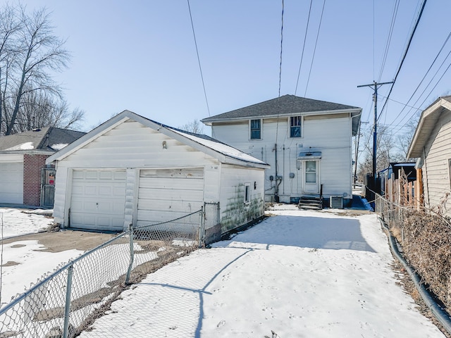 snow covered property featuring an outbuilding and a garage