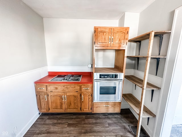 kitchen with cooktop, dark wood-type flooring, and stainless steel oven