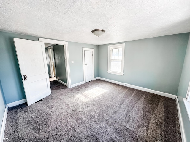 unfurnished bedroom with a closet, a textured ceiling, and dark colored carpet