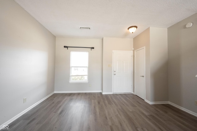 spare room featuring dark hardwood / wood-style floors and a textured ceiling