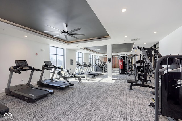 exercise room with a raised ceiling, carpet floors, and ceiling fan