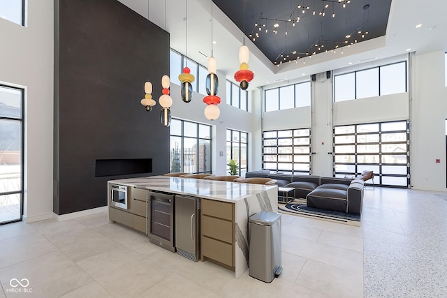 kitchen featuring a wealth of natural light, light stone countertops, beverage cooler, and a high ceiling